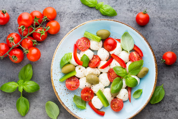 Delicious caprese salad with ripe cherry tomatoes and mini mozzarella cheese balls with fresh basil leaves.