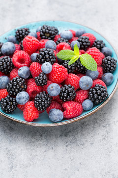Fresh berry salad on blue dishes. Vintage wooden background.