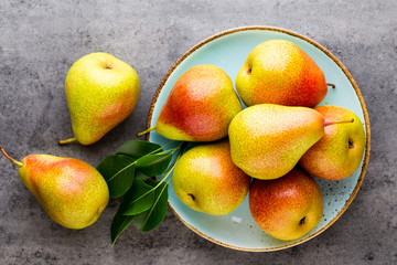 Fresh bio pear with leaves on the plate. Gray stone table.