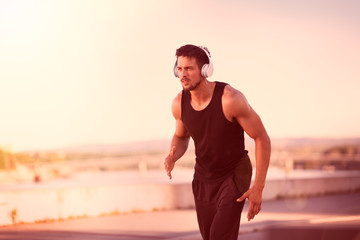 man runner listening to music on headphones, sporty fit young man jogging