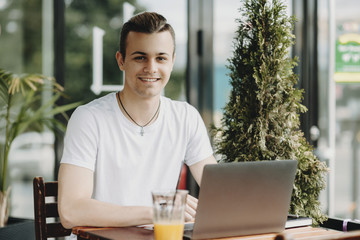 Smiling man using laptop in outdoor cafe