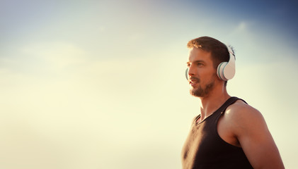 Handsome man in headphones listening to music outdoors