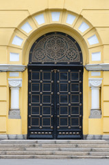 black iron door of arch type on a yellow background