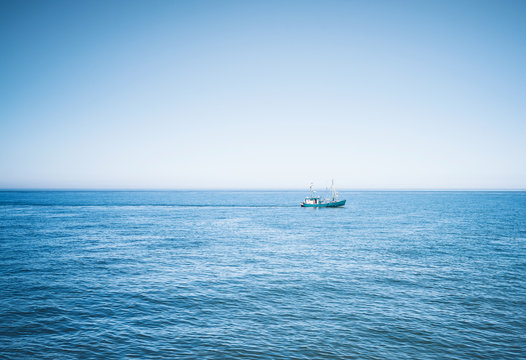 fishing vessel on wide blue ocean against clear sky