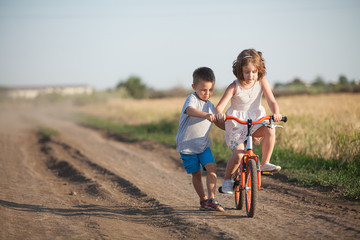  A boy and a girl ride a bicycle in the summer field