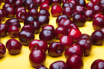 Assembled ripe red cherry on a yellow background.