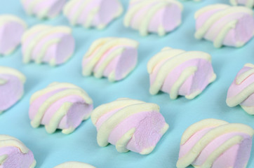 Colorful marshmallow laid out on blue paper background. pastel creative textured pattern. Perspective macro shot