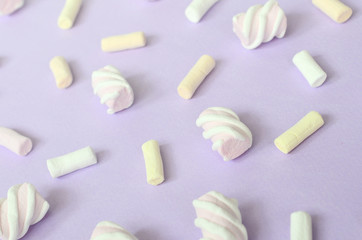 Colorful marshmallow laid out on violet paper background. pastel creative textured pattern. Perspective macro shot