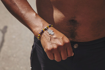 Male hand wrist with colorful bracelet and hamsa silver pendant