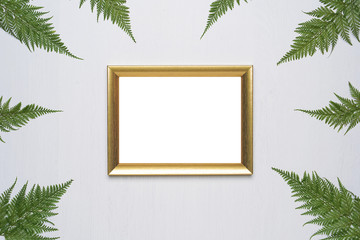 Stylish minimal composition with photo frame and green leaves on a white wooden background. Empty photo frame and green leaves. flat lay, top view.