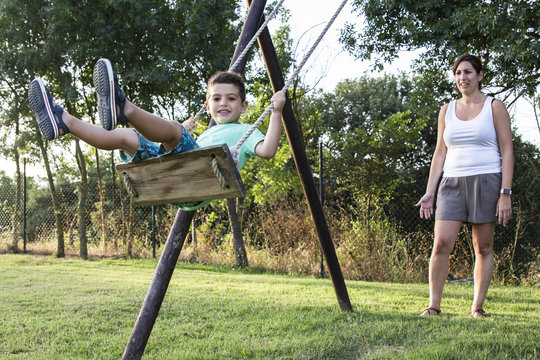 Mother swinging her son on a swing