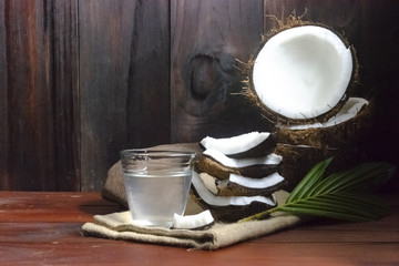 Coconut water or coconut juice and coconut half and coconut pieces and leaf  on wooden table and black wooden background.