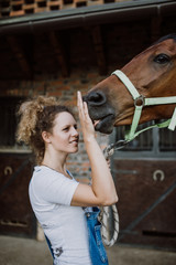 Young woman taking care of her beautiful horse.