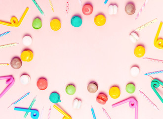Bright birthday accessories, candels and macarons on pink background