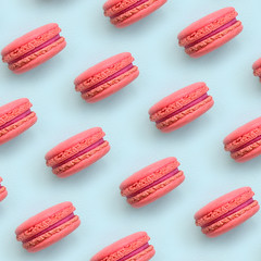Pink dessert cake macaron or macaroon on trendy pastel blue background top view. Flat lay pattern composition