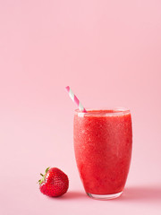 Strawberry smoothie and fresh raw berries on pink