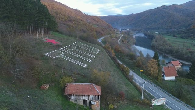 Drone shot of traffic driving past Tito monument in village in Bosnia and Herzegovina