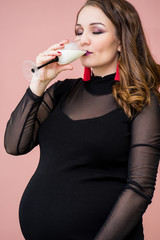 Beautiful young pregnant woman drink milk in a  champagne glass. Pregnant woman celebrating her pregnancy