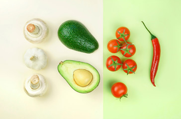 Creative layout composition made of vegetables cherry tomato, pepper, mushrooms and avocado on light green and beige background top view, flat lay.