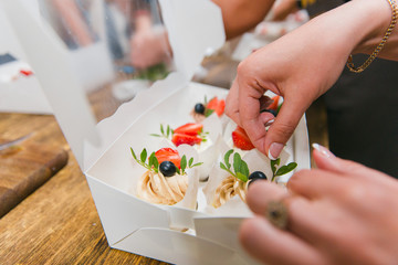 Girls prepare beautiful and tasty desserts on a wooden table and decorate with fruits