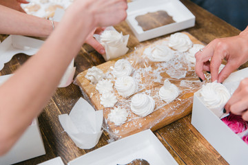 Girls prepare beautiful and tasty desserts on a wooden table and decorate with fruits