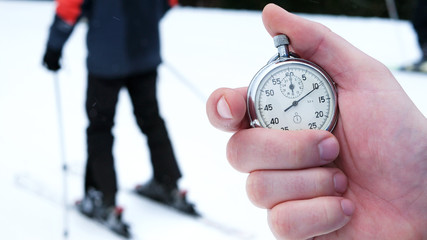 One person starting up a stopwatch in hand on a ski slope. Man pushing timer button outdoors. The...