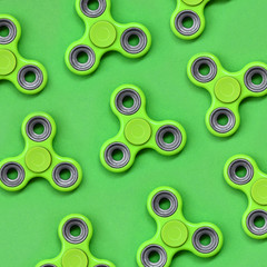 Many green fidget spinners lies on texture background of fashion pastel green color paper in minimal concept