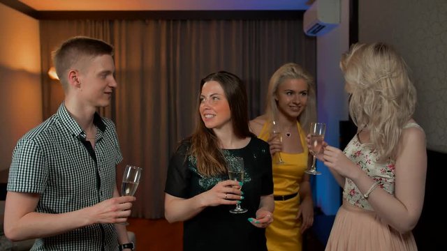 Group of happy friends with cocktails toasting at party. They happy of common conversation with sparkling champagne. Two sexy ladies and young couple greetings.