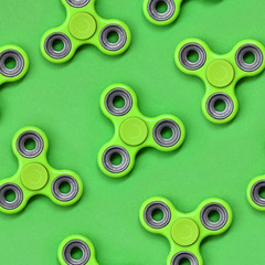 Many green fidget spinners lies on texture background of fashion pastel green color paper in minimal concept