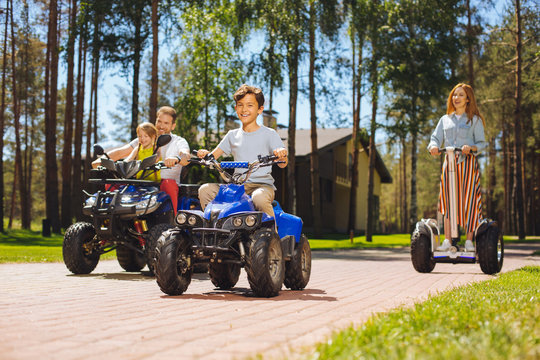 We Adore Driving. Delighted Cute Kids Spending Time With Their Parents And Driving ATVs