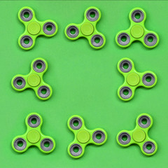 Many green fidget spinners lies on texture background of fashion pastel green color paper in...