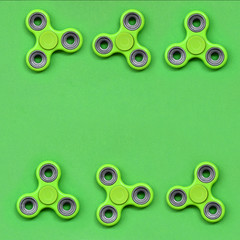 Many green fidget spinners lies on texture background of fashion pastel green color paper in...