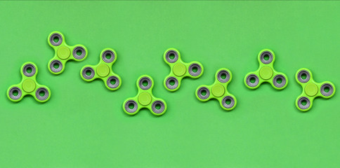 Many green fidget spinners lies on texture background of fashion pastel green color paper in...