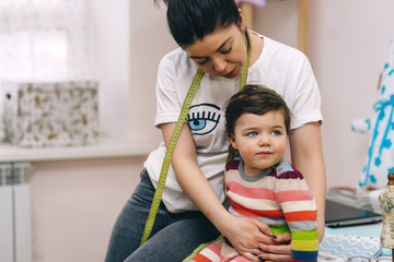 Young mother designer with her daughter at her workshop