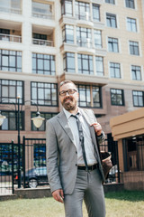 handsome bearded businessman in suit with leather bag in city