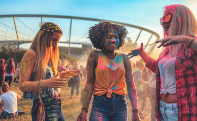 Multiethnic group of friends with colorful powder on clothes and bodies at summer holi festival...