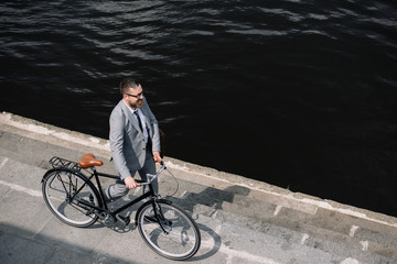 overhead view of businessman walking with bike on quay near river