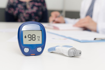 Glucometer and lancet pen. Doctor and patient at office.