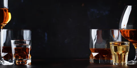 Foto op Plexiglas Bar Set van sterke alcoholische dranken in glazen en borrelglas in assortiment: wodka, rum, cognac, tequila, cognac en whisky. Donkere vintage achtergrond, selectieve focus