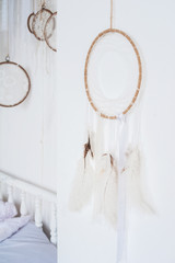 White textured bedroom in the style of shabby. Bed in an ecological style and Loft style. Rustic dream catchers on a white wall. screen diy