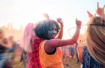 Multiethnic girls covered in colorful powder celebrating summer holi festival