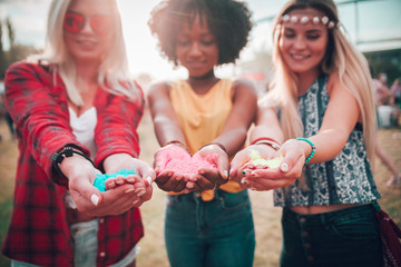 Happy multiethnic group of friends holding colorful powder in hands at holi festival