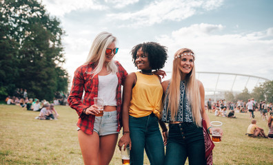 Group of friends with beer in hands at summer music festival outdoor