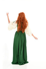 full length portrait of red haired girl wearing long green gown,. standing pose with back to the camera, isolated on white studio background.