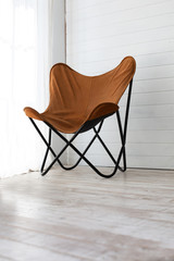 Simple folding armchair in a room with wooden floor and window