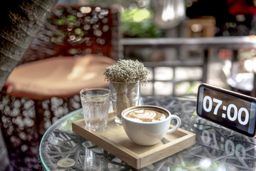Cup of coffee with hot latte art in cafe shop or restaurant at 07.00 o'clock
