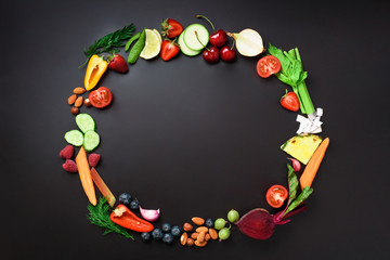 Healthy food background. Circle of organic vegetables, fruits, nuts, berries with copy space on black chalkboard. Top view. Vegetarian, vegan, detox and clean eating concept