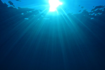 Underwater sunburst in blue sea 