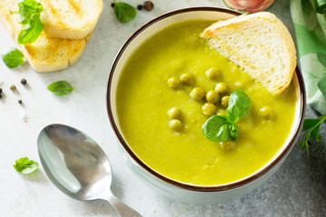 Puree soup green peas with croutons in a bowl close-up on a light slate background. Diet menu. The concept of healthy eating.