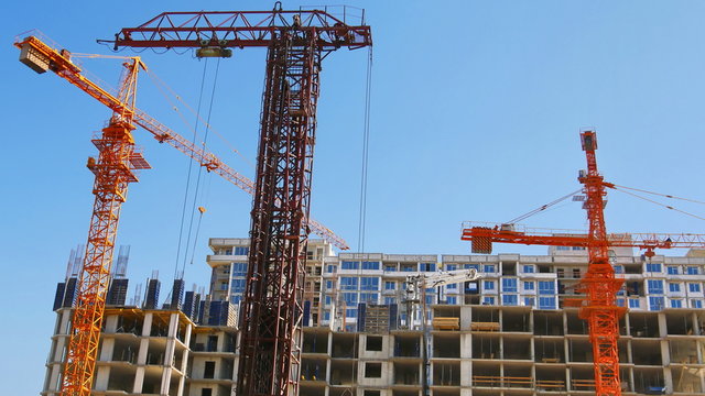  Concrete buildings under construction. Industrial cranes and a building under construction. Construction site.